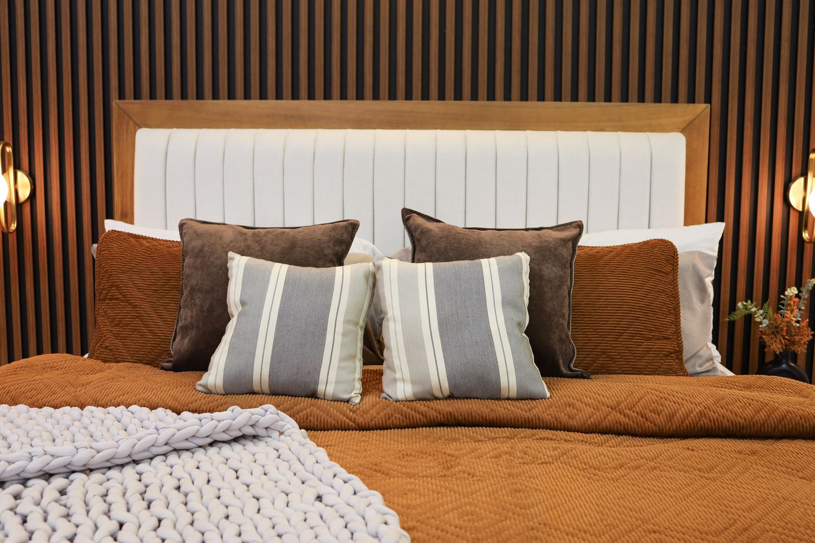 Beautifully layered bed with white linens, chunky knit throw blanket, and euro pillows in a cozy bedroom