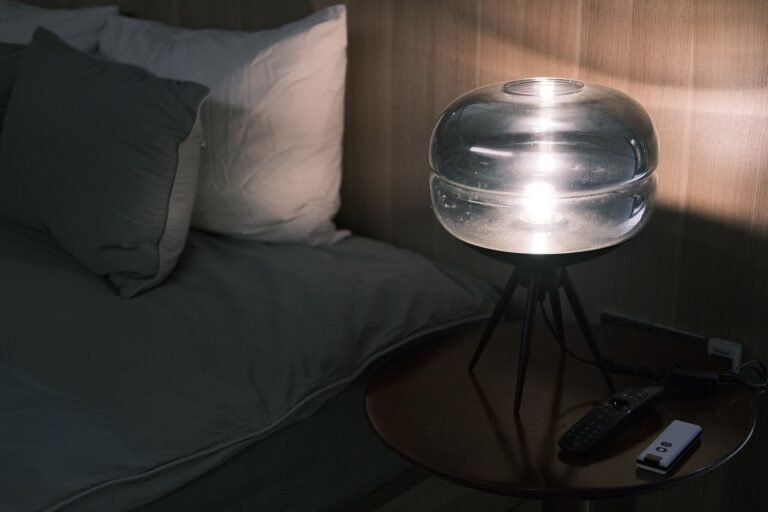 Warm bedside reading light illuminating an open book on soft pillows in a cozy bedroom at night