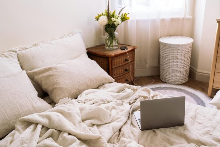 Rumpled stonewashed linen bedding in soft neutral tones on a cozy bed with morning light