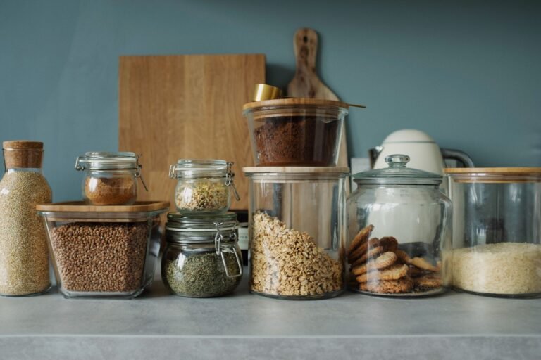 Neatly organised small pantry with labelled airtight containers and tiered shelving in a bright kitchen