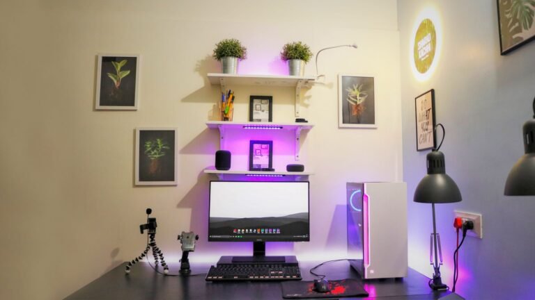 Bright minimalist home office with wooden desk, monitor stand, and warm desk lamp near window