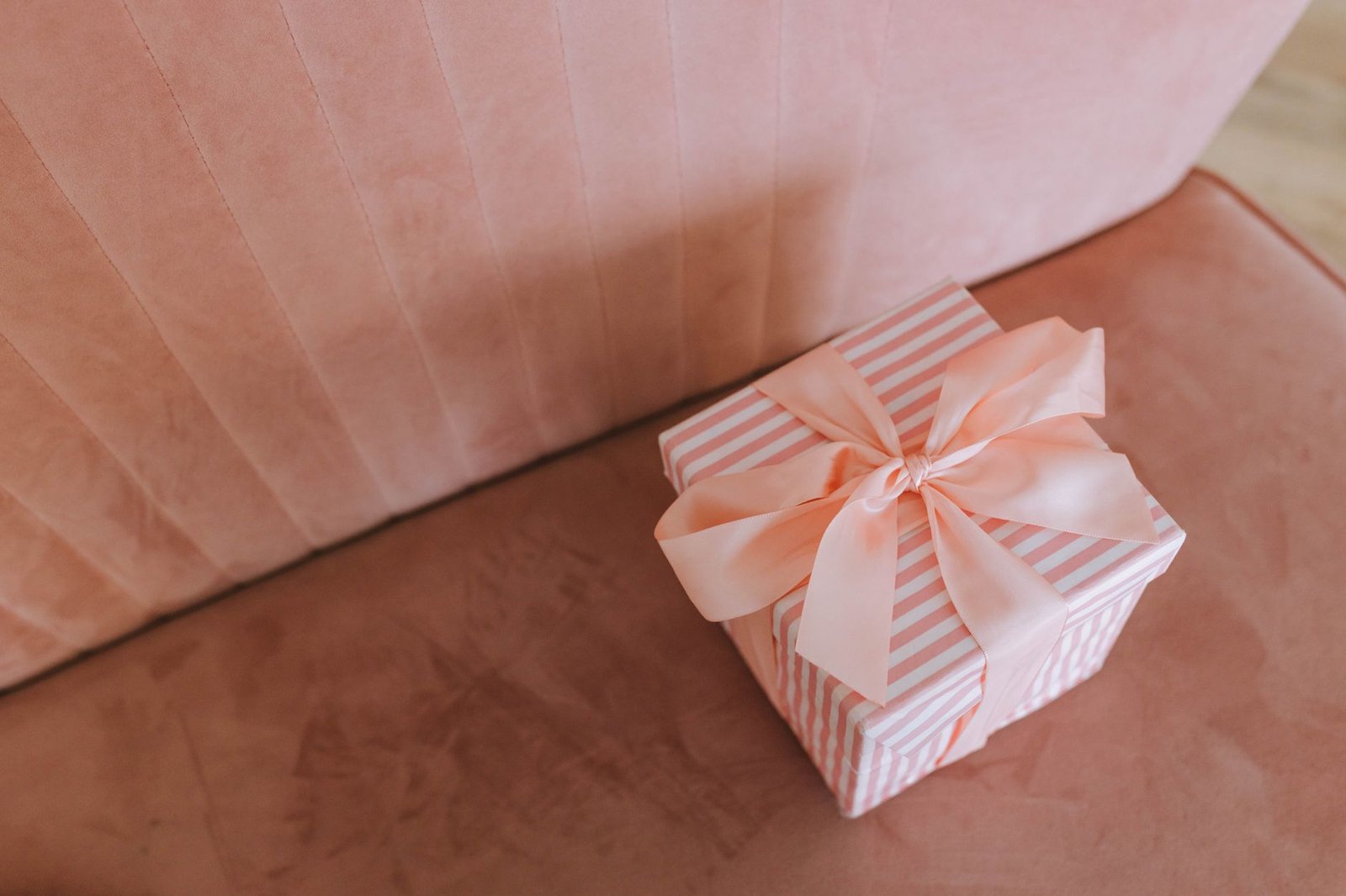 Wrapped housewarming gifts with candles and greenery arranged on a wooden table in a bright living room