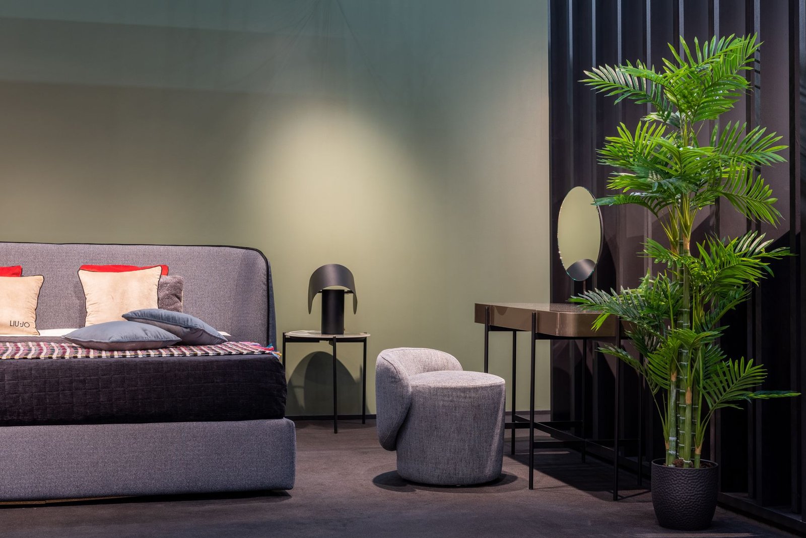 Lush green bedroom plants on a wooden nightstand beside a cozy unmade bed with white linens