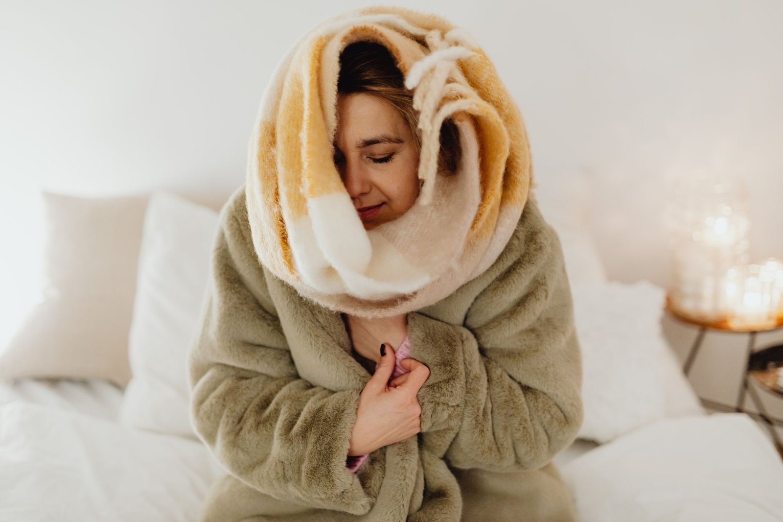 Soft weighted blanket draped over a cozy bed with neutral bedding and warm ambient lighting