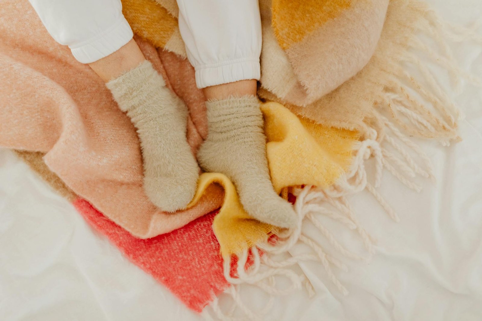 Soft chunky knit throw blanket draped over a cozy sofa with warm lighting creating a hygge winter atmosphere
