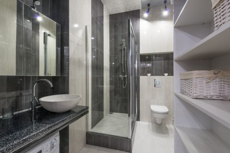 Clean organised bathroom with white shelves, neatly arranged toiletries, and fresh towels in a bright modern space
