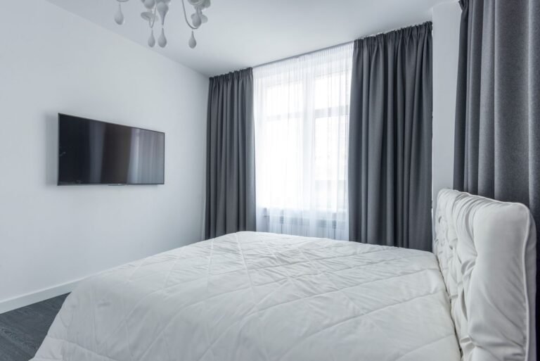 Soft blackout curtains framing a bedroom window with warm morning light filtering through the edges