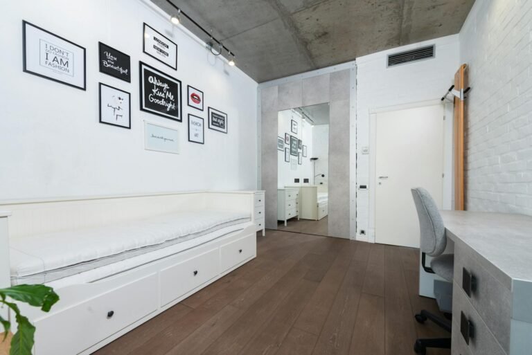 Neatly organised bedroom with floating shelves, folded blankets, and warm ambient lighting creating a cosy retreat