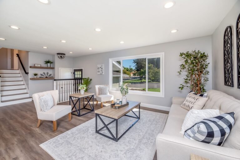 Bright living room with white linen cushions, rattan accents, and sheer curtains letting in natural summer light