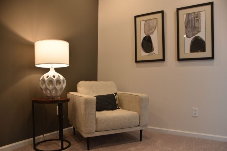 Warm living room corner with floor lamp, cushions, and floating shelves creating an inviting reading nook