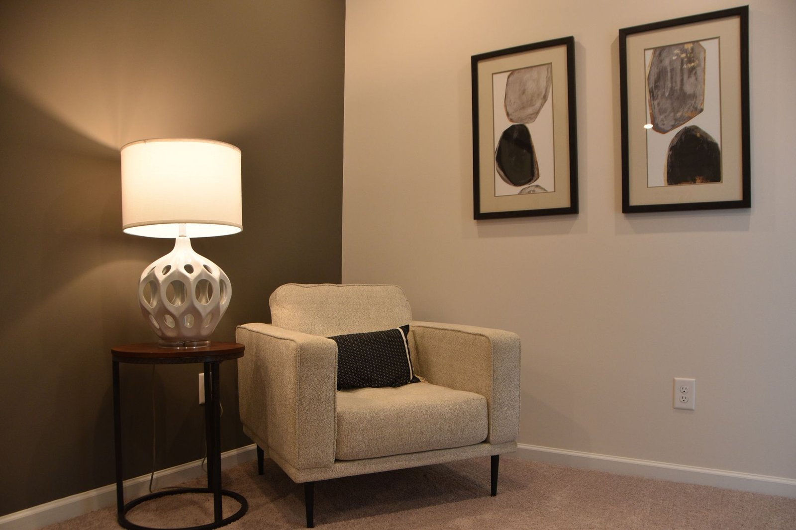Warm living room corner with floor lamp, cushions, and floating shelves creating an inviting reading nook