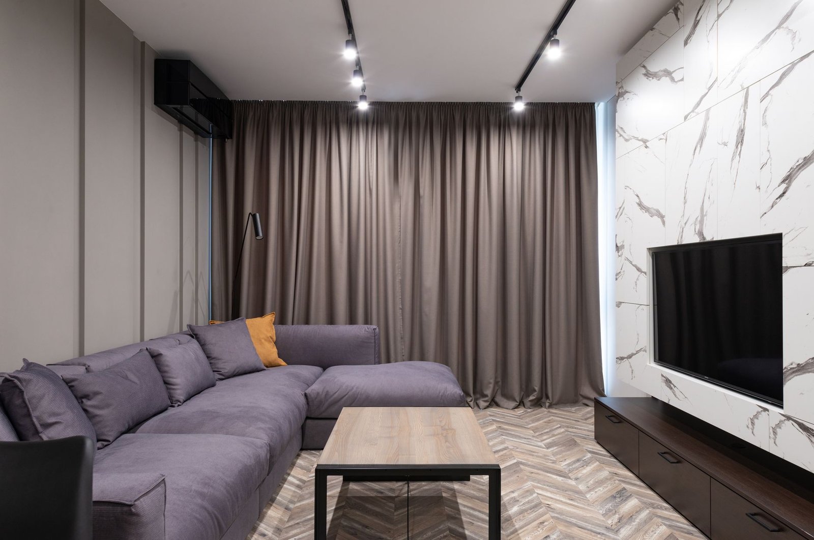 Warm rented flat living room with layered textiles, floor lamp, and freestanding bookshelf creating cozy atmosphere