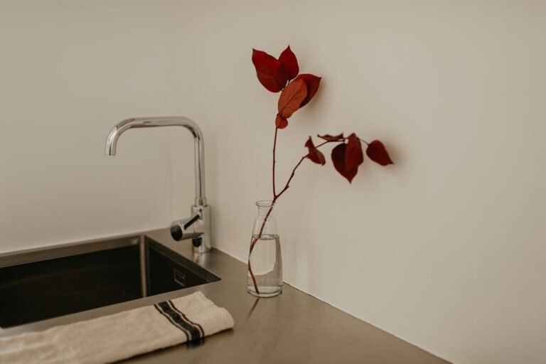 Clean minimalist kitchen counter with just a kettle and wooden cutting board in morning light